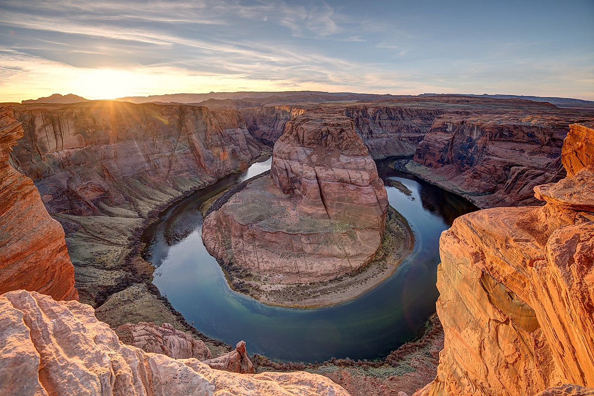 Evening light illuminates the sandstone cliffs of Horseshoe Bend as the Colorado River curves around the canyon near Page, Arizona.